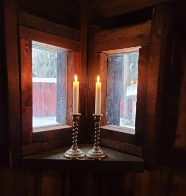 Kaksi kynttilää palaa ikkunalaudalla.